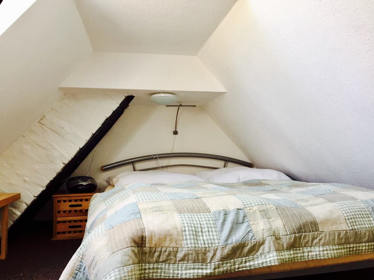 Doppelbett auf dem Spitzboden unter dem Dach